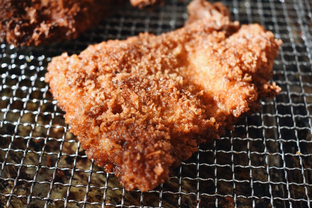 breaded and fried chicken thighs cooling on a cooling rack after cooking