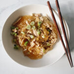 Chicken long rice in bowl with chopsticks on the side of the bowl